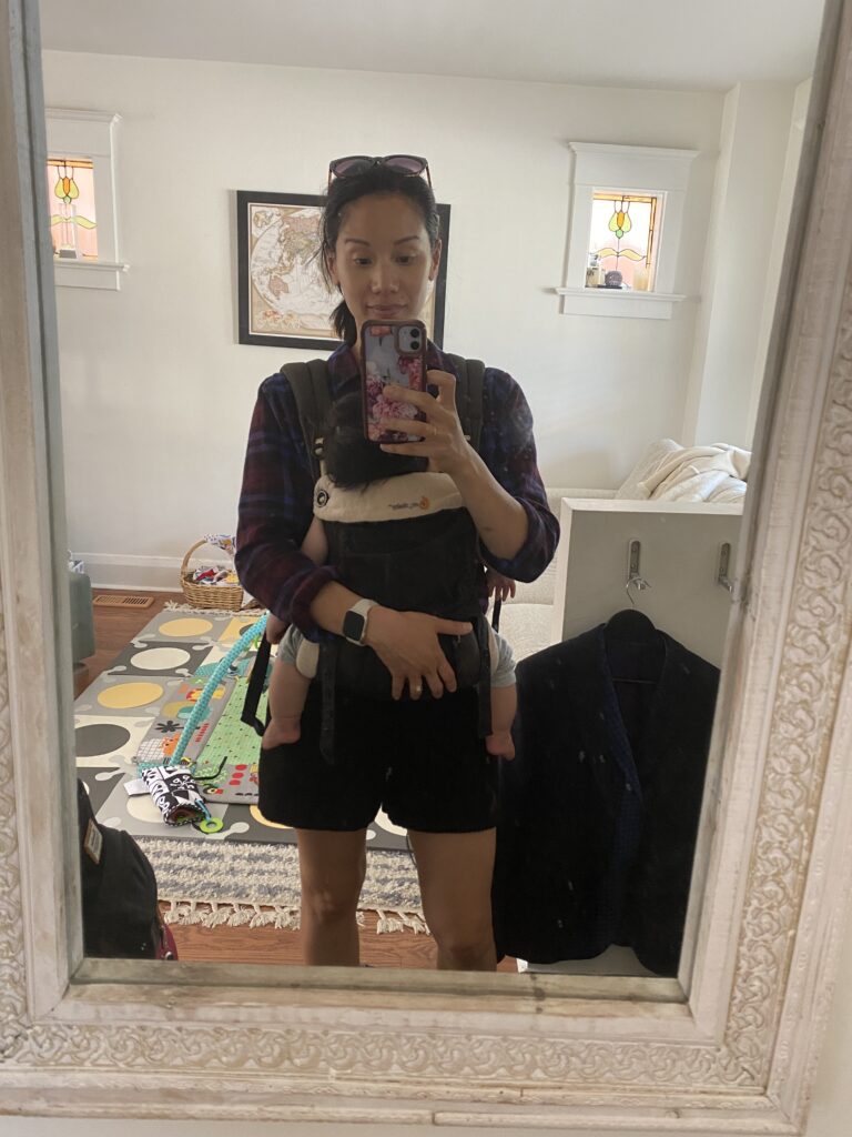 Me taking a selfie in the mirror holding my baby in a carrier.